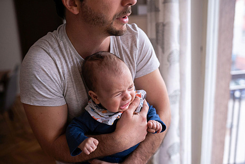 Junger Vater hält weinendes Baby