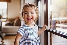 Ein Kind steht am Fenster und lächelt