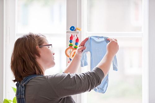 Eine Schwangere schaut Babykleidung an