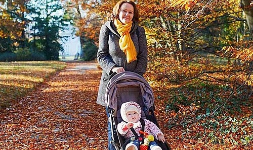 Frau mit Kinderwagen im Park