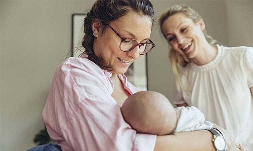 Eine Stillberaterin hilft einer jungen Mutter beim Anlegen ihres Babys.