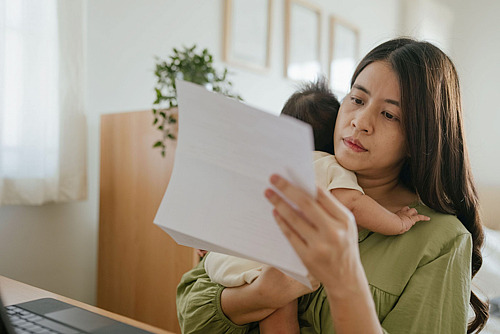 Frau mit Baby im Arm prüft ihre Finanzen