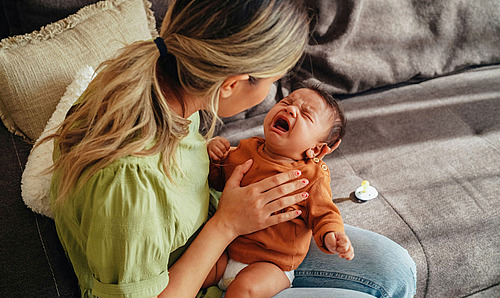 Mutter versucht ihr weinendes Baby zu beruhigen