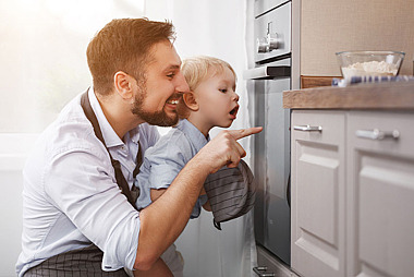 Vater und Kind vor einem Backofen 