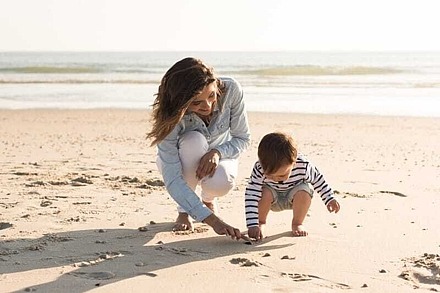 Eine Mutter und ihr Kind suchen Muscheln am Strand