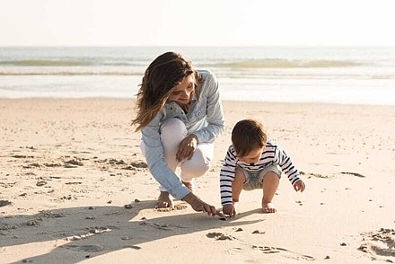 Eine Mutter und ihr Kind suchen Muscheln am Strand