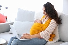 Mutter mit Baby nutzt Laptop zu Hause
