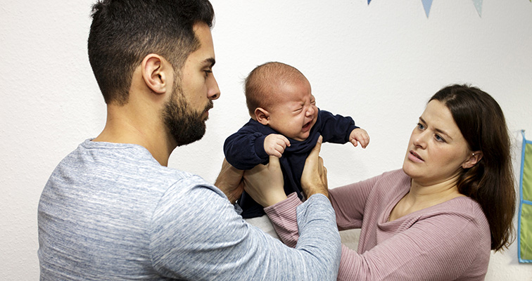 Schüttteltrauma Mann und Frau halten gemeinsam schreiendes Baby hoch
