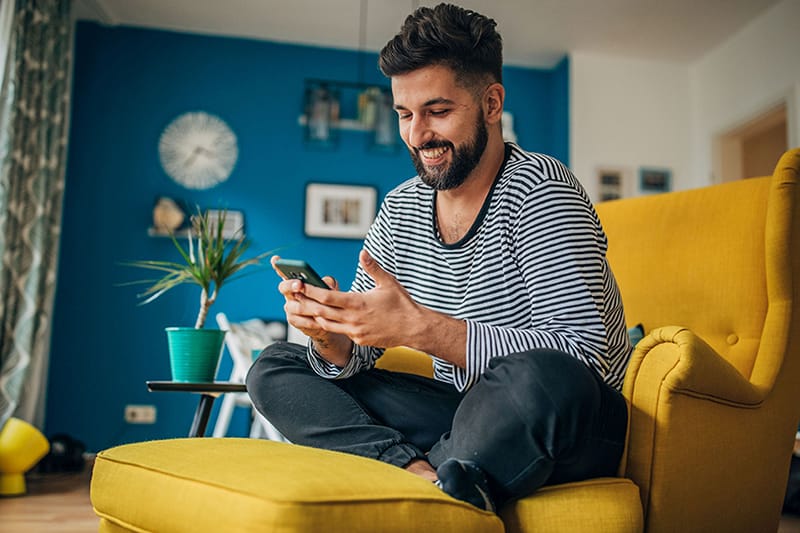 Ein lachender Mann schaut auf sein Smartphone