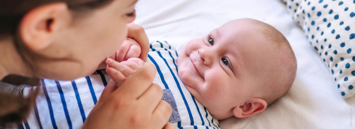 Familienhebammen helfen Mutter und Kind Frau hält Baby an den Händen