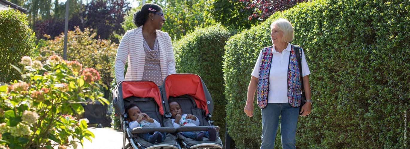 Mutter mit Zwillingen und Familienpatin Mutter mit Zwillings-Kinderwagen spricht mit Familienpatin