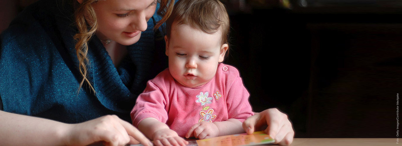 Mutter liest mit ihrem zehn Monate alten Baby ein Buch