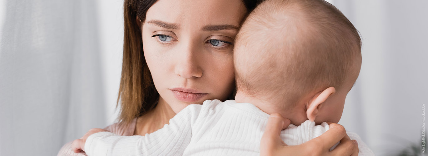 Erschöpfte und traurige Mutter mit ihrem Baby