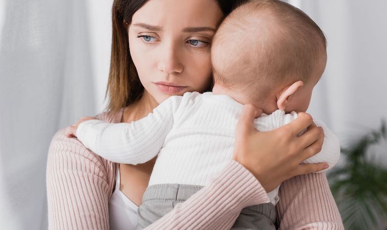 Erschöpfte und traurige Mutter mit ihrem Baby