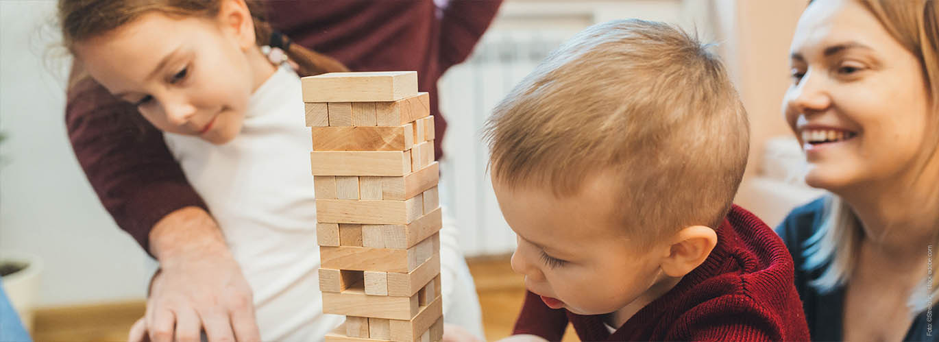 Mutter beobachtet ihre Kleinkinder beim Bauklötze Spiel