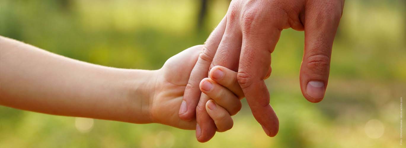 Eine Kinderhand hält zwei Finger von einer Männerhand