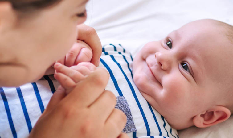 Frau hält Baby an den Händen