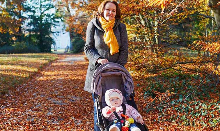 Frau mit Kinderwagen im Park