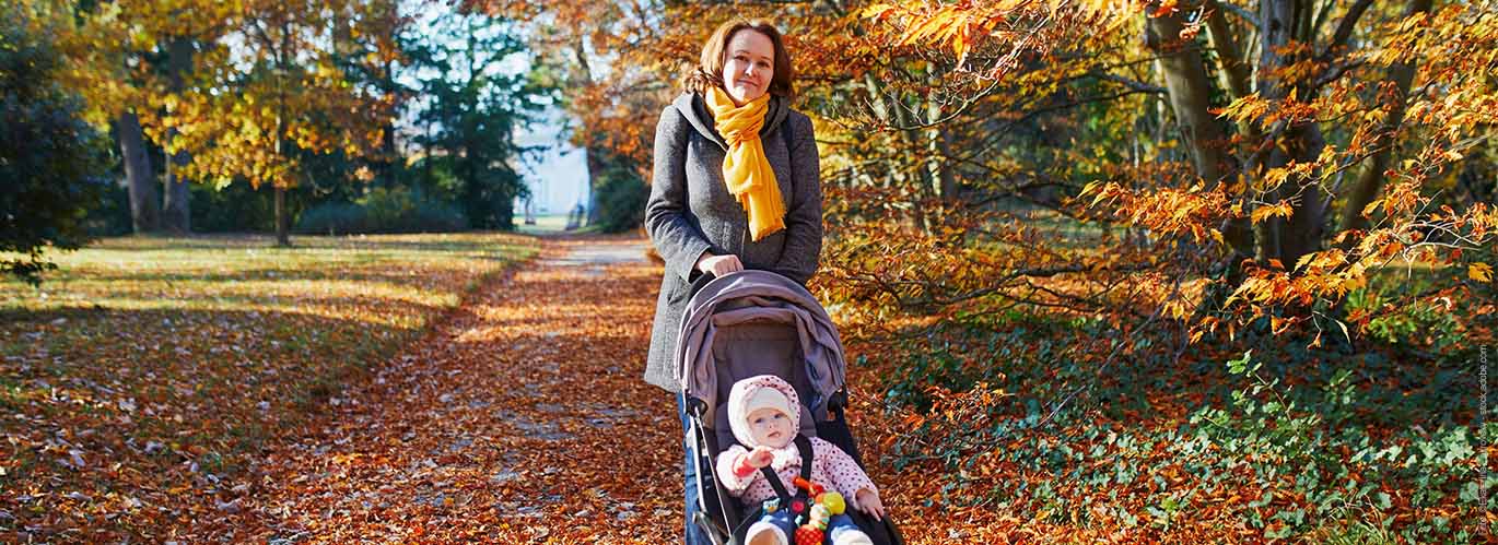 Frau mit Kinderwagen im Park