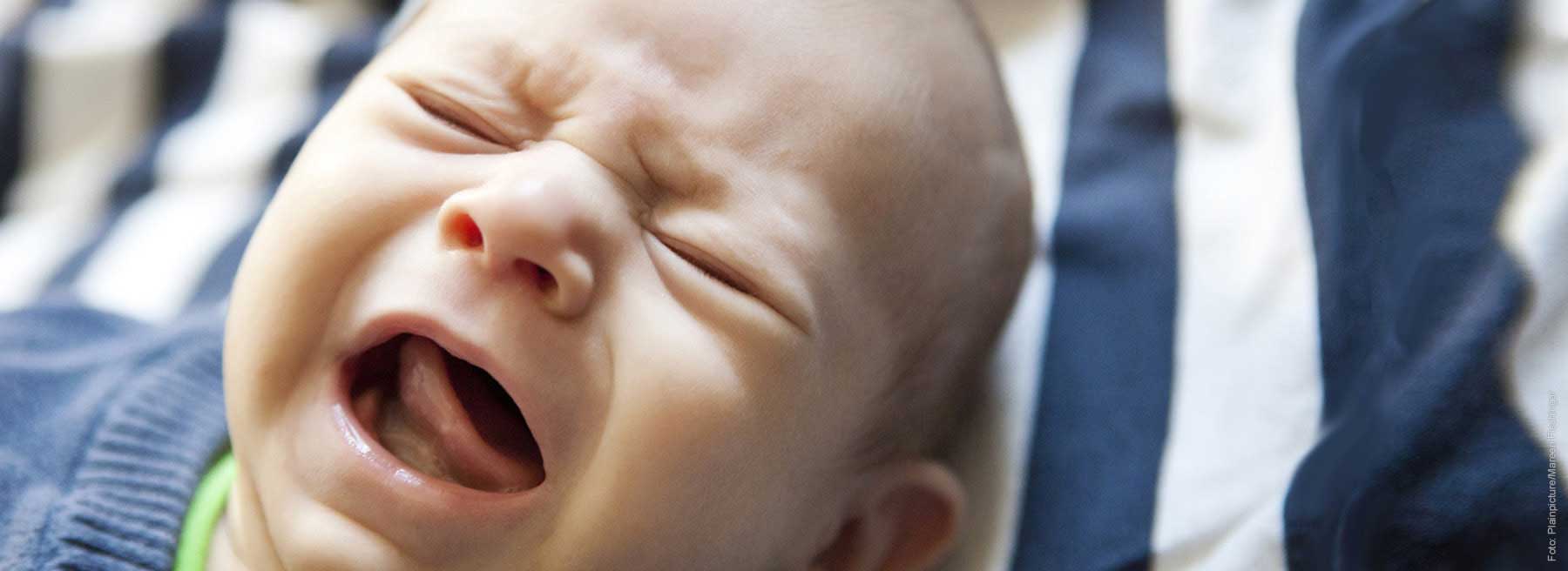 Hilfe bei Schreibabys Schreiendes Baby auf blau-weiß gestreifter Decke