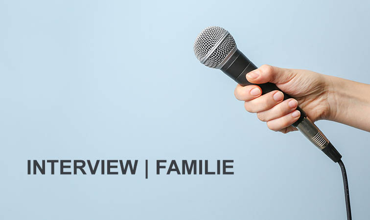 Eine Hand hält ein Mikrofon. Auf dem Hintergrund steht folgender Text: Interview Familie