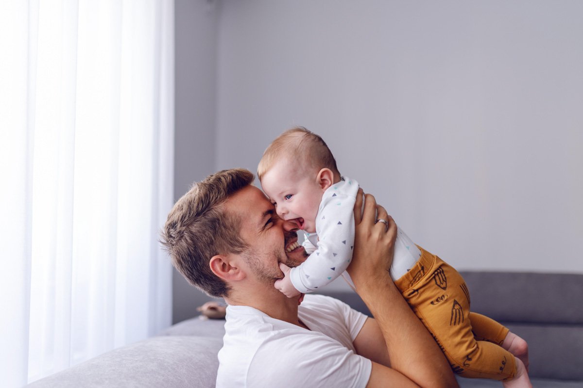 Schon Babys genießen das gemeinsame Spielen. Vater knuddelt sein Baby.