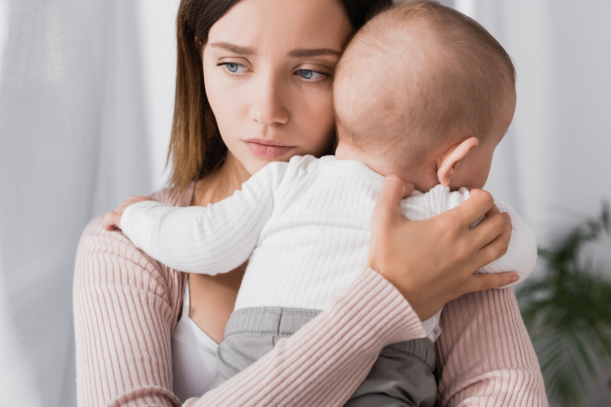 Besorgte Mutter hält Baby im Arm