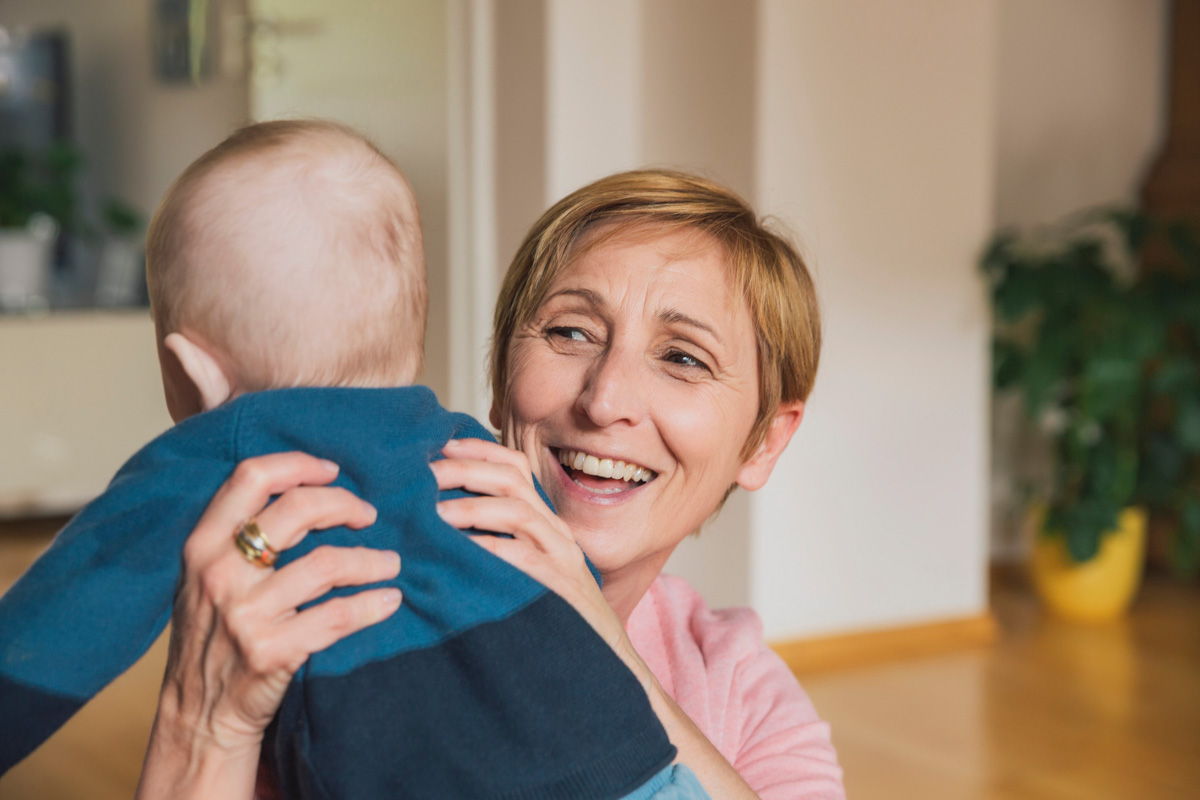 werden Sie Familienpatin oder Familienpate Eine Frau hält lächelnd ein Baby hoch