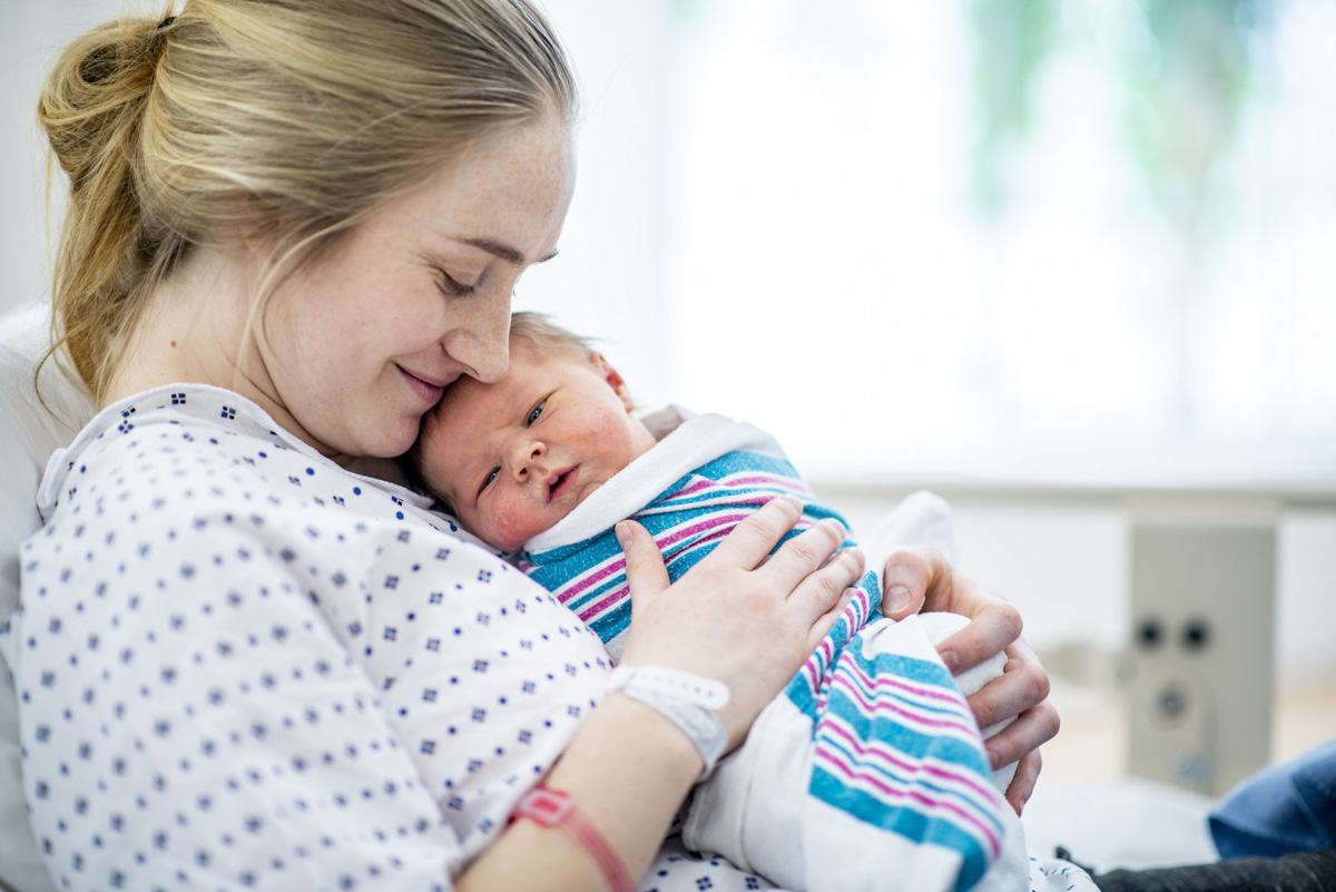 Immer mehr Geburtskliniken haben einen Lotsendienst Frau hält neugeborenes Baby im Arm
