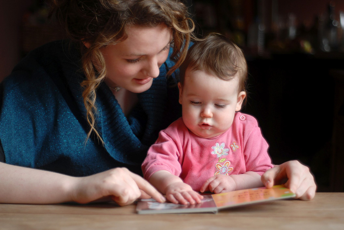 Vorlesen macht Eltern und Babys Freude Junge Mutter liest ihrem Kind ein Buch vor.