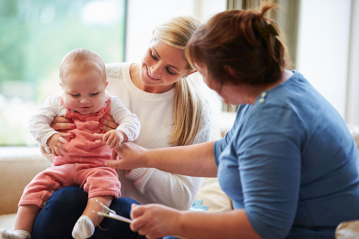 Familienhebammen helfen Mutter und Kind Frau hält Baby an den Händen