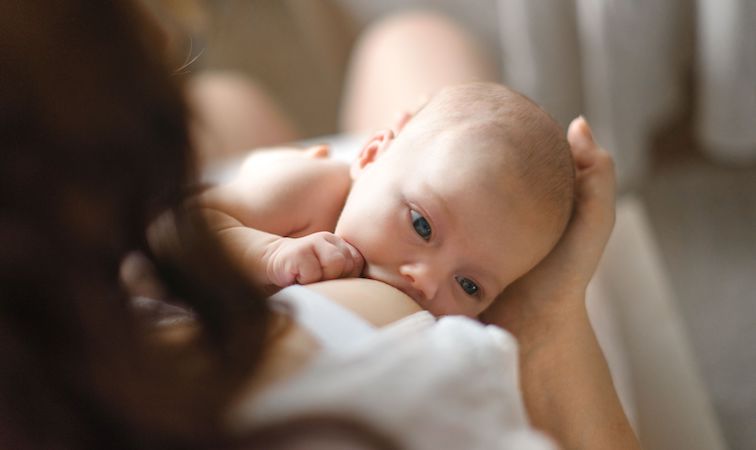 Eine Mutter stillt ihr Neugeborenes