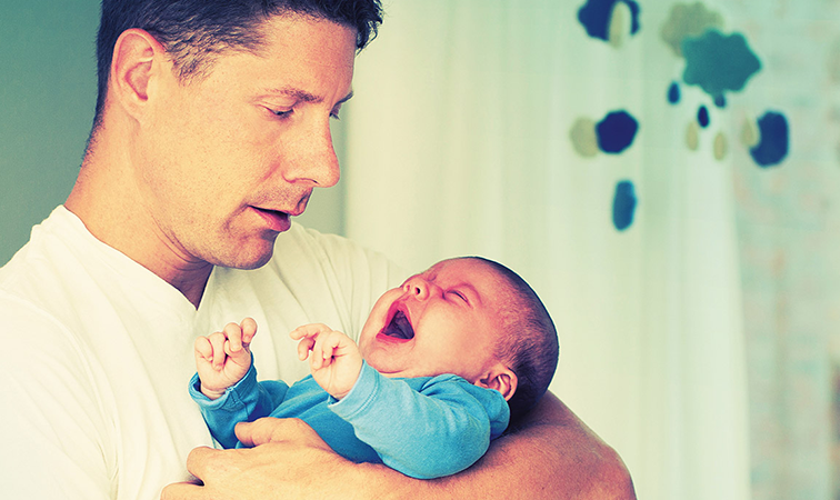 Vater mit schreiendem Baby auf dem Arm